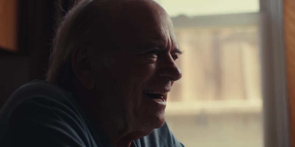 Elderly man sitting happily using a smartphone