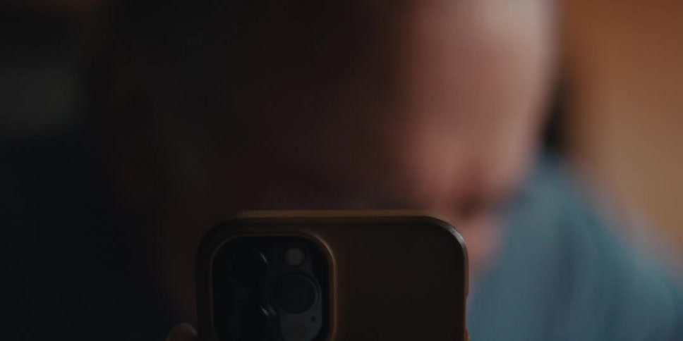 A man walks over and smiles in front of his cell phone