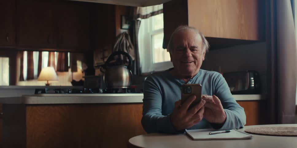 Elderly man sitting and smiling while using a smartphone