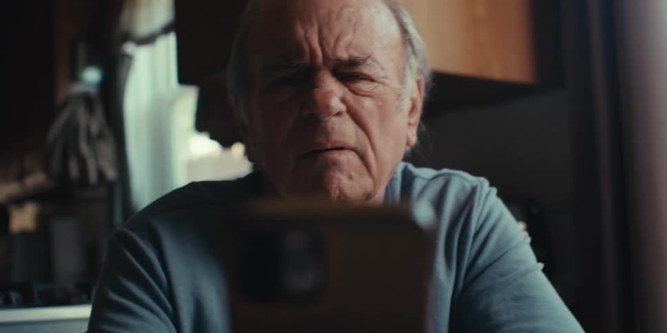 Elderly man is squinting as he tries to read a text on the phone