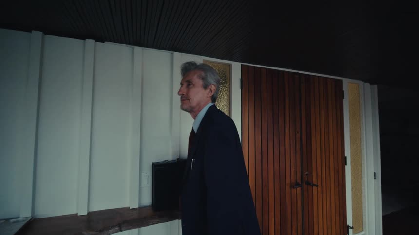 Man in suit inside house answering a phone call