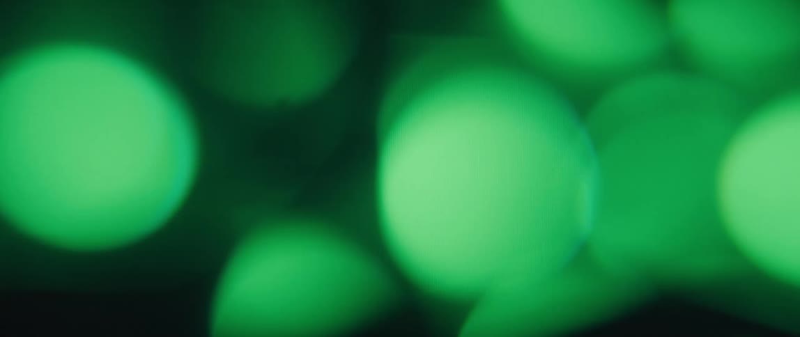 A blurred background with a cluster of green orbs creating a dreamy and atmospheric effect
