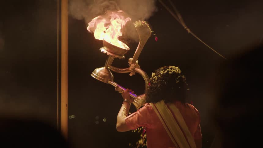 Woman performing with a chalice of fire in an outdoor area at night