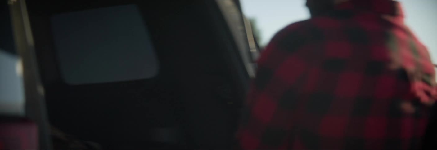Woman and man taking backpacks out of car trunk