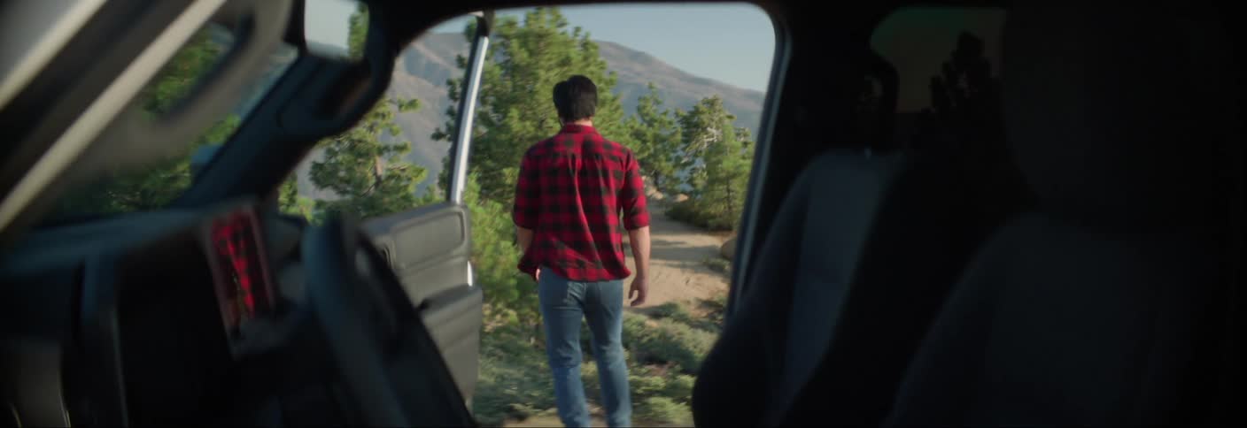 View through a car of a man and a woman walking on a nature trail
