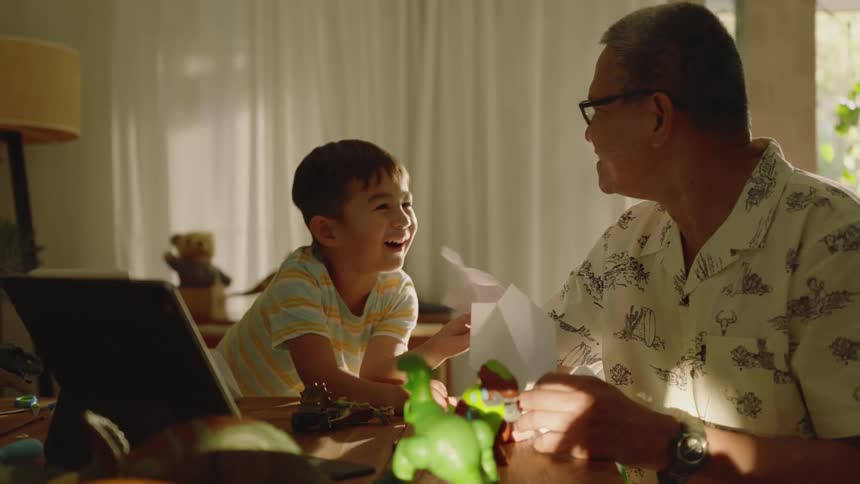 Father and son sitting at table interacting with a tablet