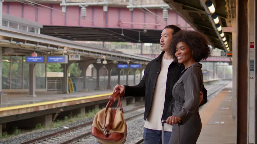 Couple standing together next to a train track at a subway station