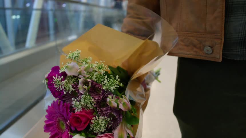 Man holding bouquet of flowers waiting for someone at the airport