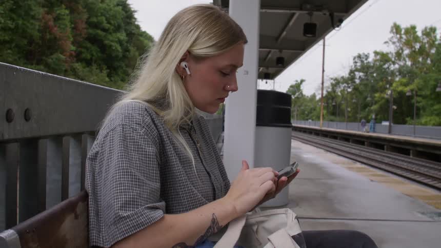A woman is using her cell phone while waiting for a train