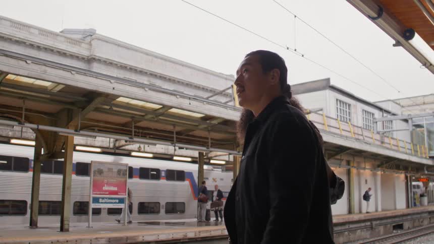 A couple stands on a train platform waiting for the train
