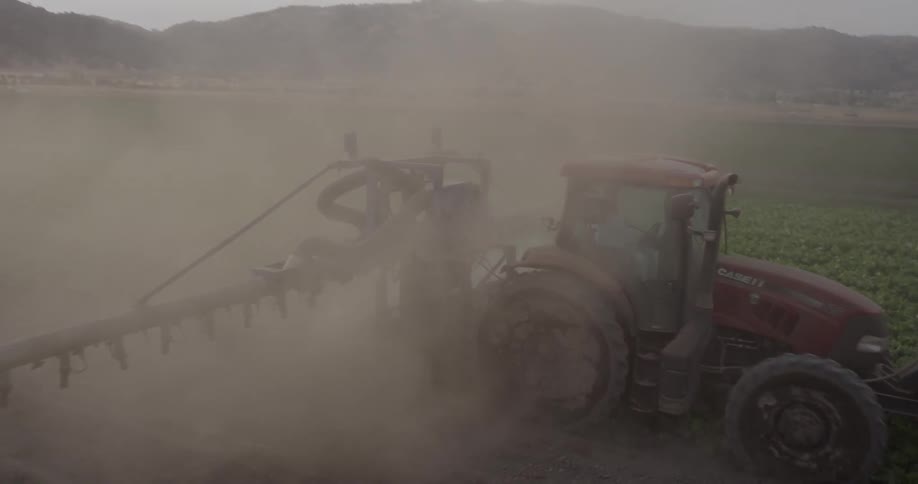 A tractor drives through a crop field