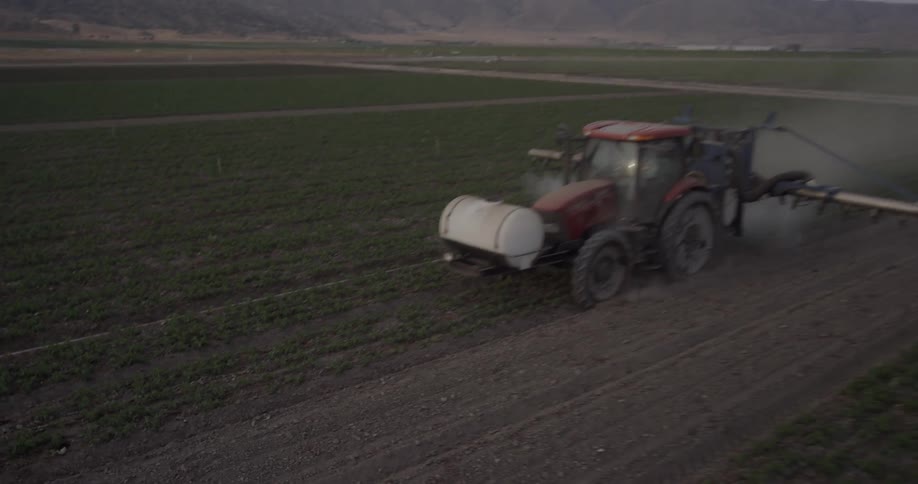 A tractor sprays fluid onto crops