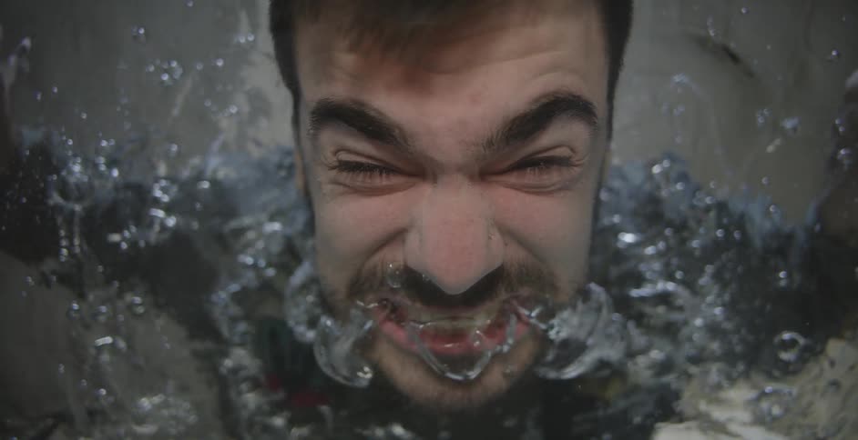 A man underwater and screaming and looking up at the camera
