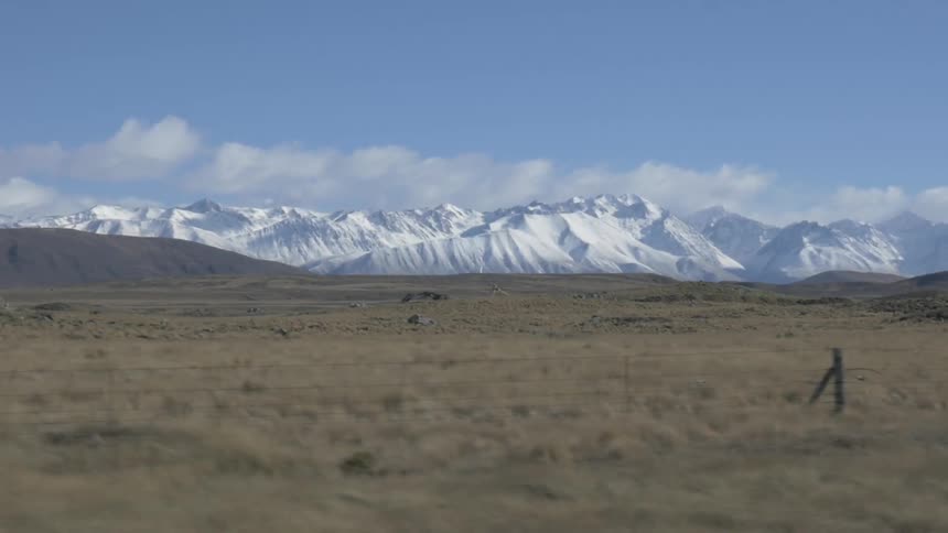A snow covered mountain is seen across farmland