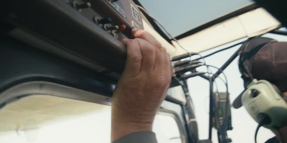 Man holds his fingers against switches while flying a small airplane