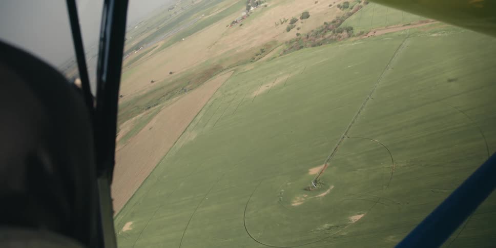 An aerial view of agricultural fields with circular irrigation patterns taken from an aircraft in flight