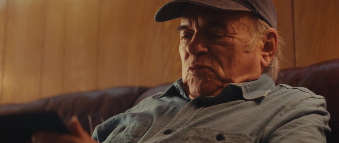 An elderly man sitting on a couch at home using a tablet
