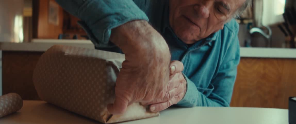 Old man tapes one end of a wrapped package