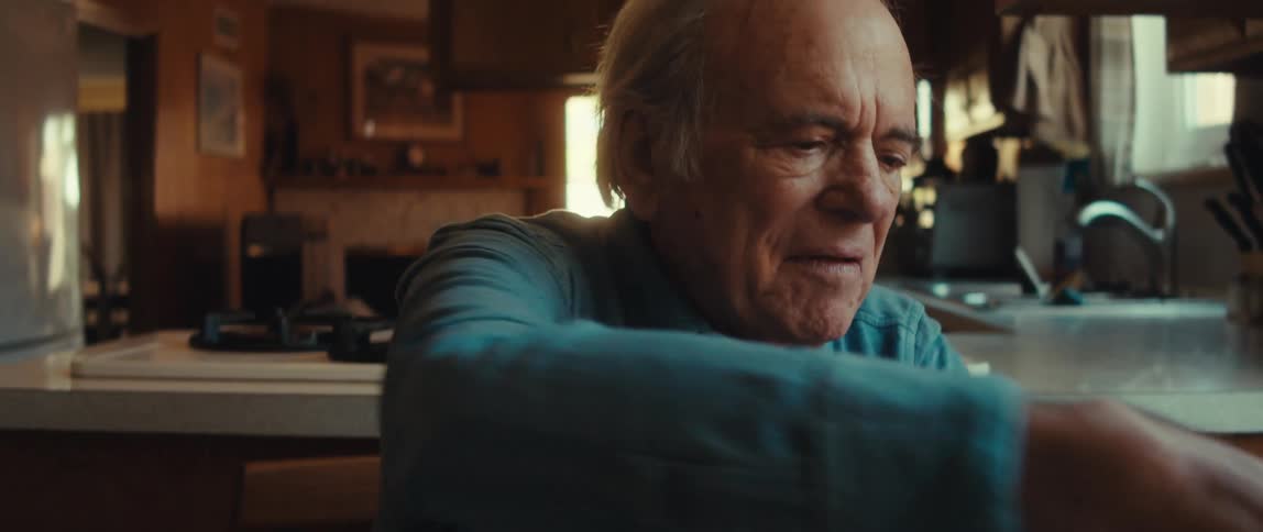 An elderly man wrapping a present at home