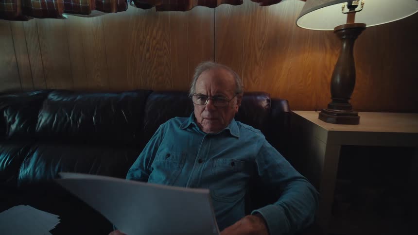 Man sitting on his living room couch reading papers