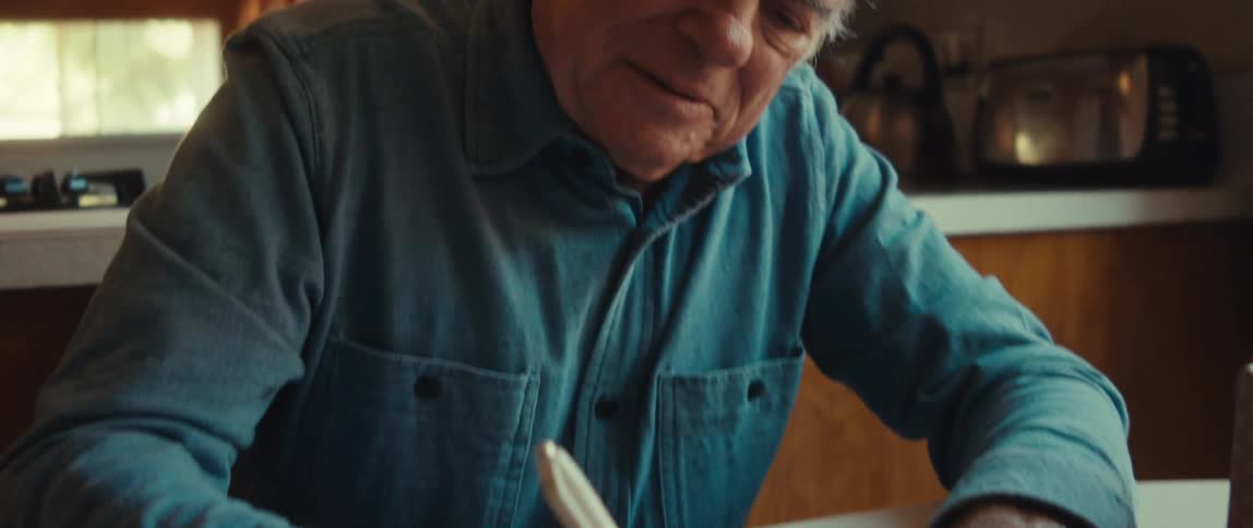Elderly man sitting writing a note