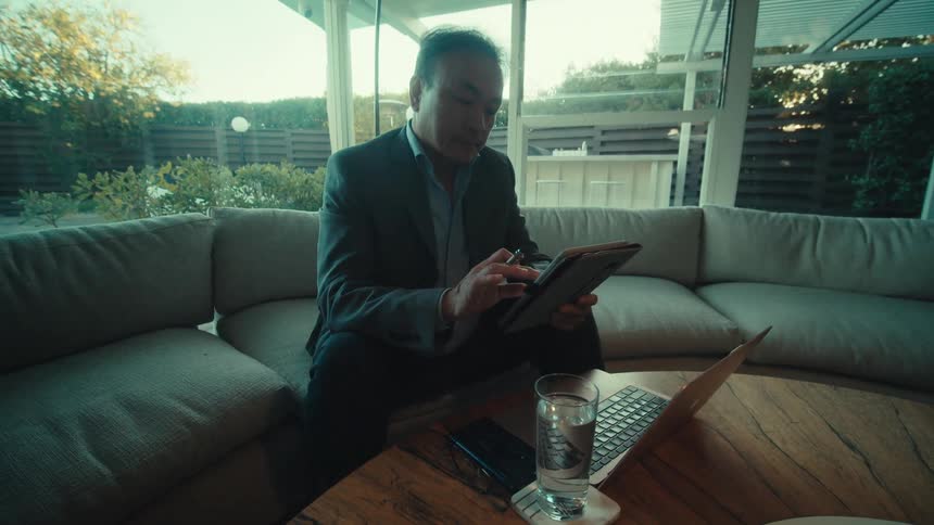 A man is using a tablet and a laptop at home
