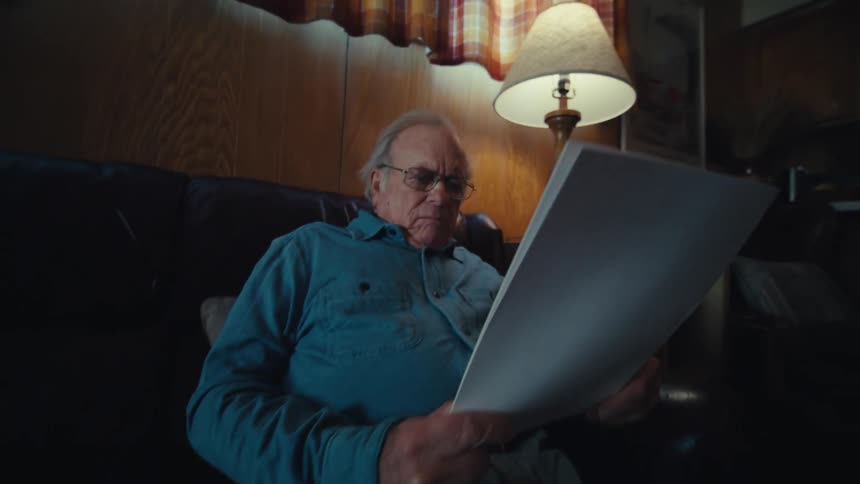 A man is sitting on the couch reading papers