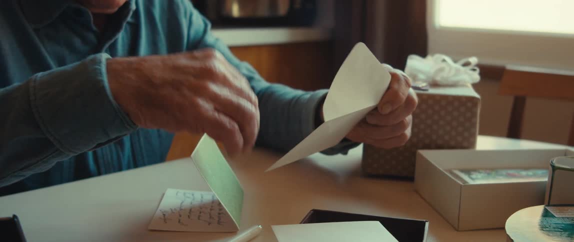 Elderly man sitting down taking a letter from a box