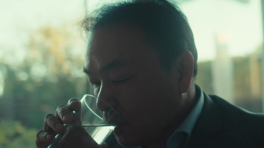 A man looks at his tablet and takes a drink of water