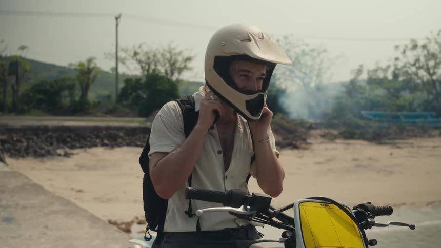 A man stops his dirt bike and removes his helmet