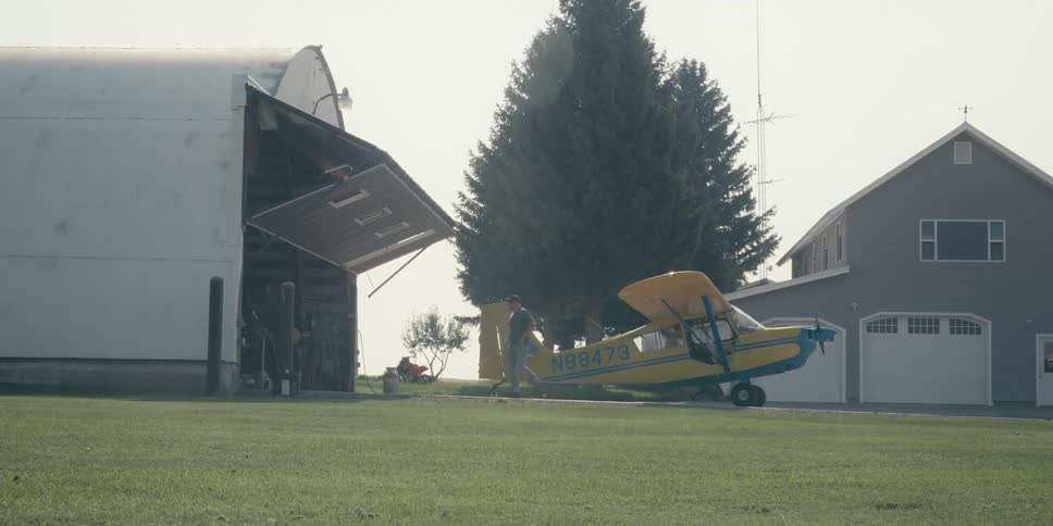 A prop plane outside its hangar