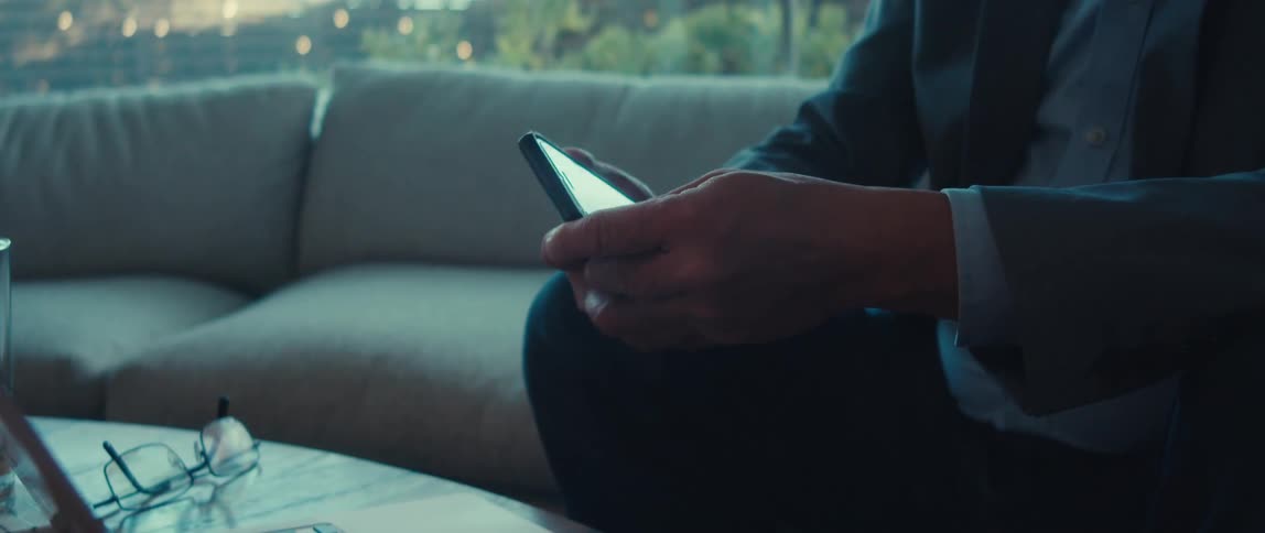 Hand using a smartphone while leaving it aside and typing on a laptop