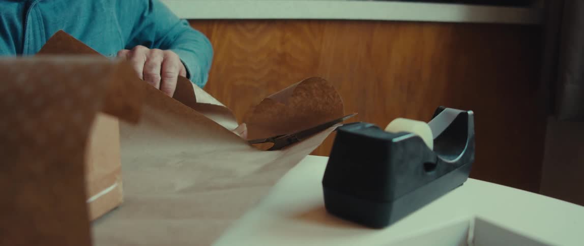 Old man happily cuts wrapping paper with scissors