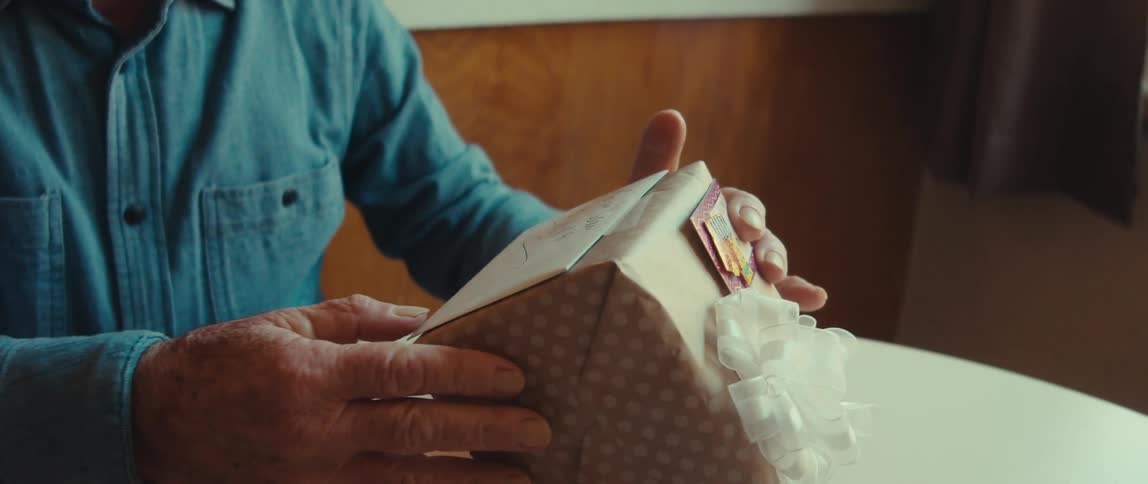 Closeup of an elderly mans hands packing a gift box at home