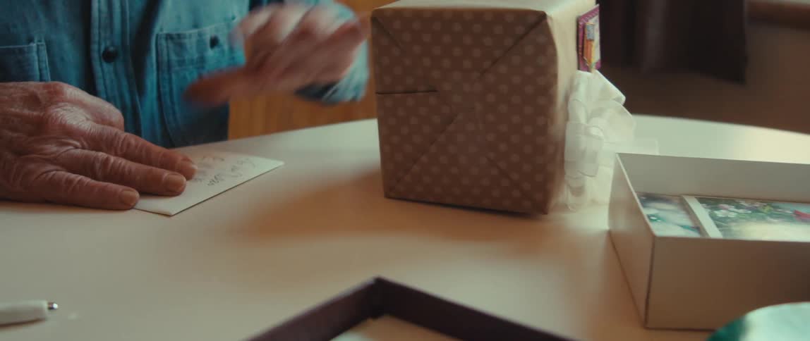 The hands of a person gluing paper on top of a gift box