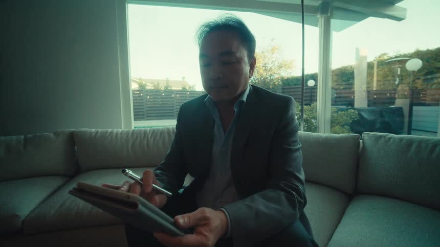Man sitting on a sofa interacting with a tablet