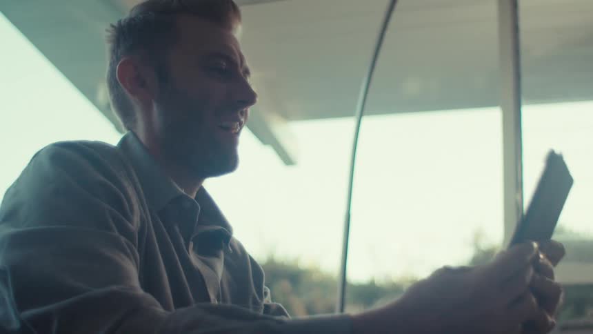 Man sitting interacting and talking with a tablet in his hands