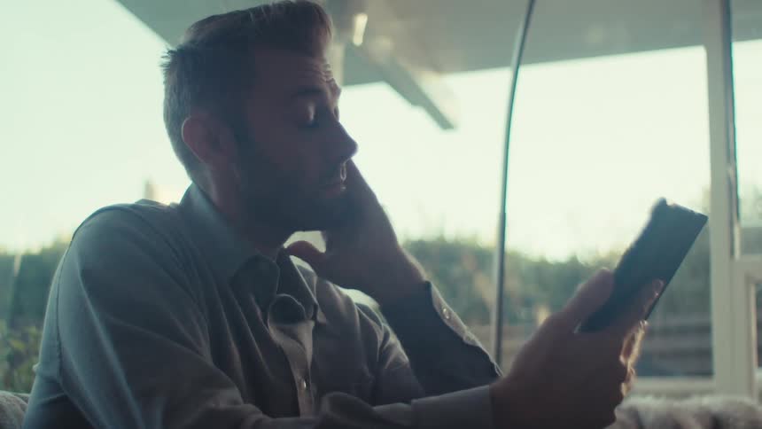 A man is shaking his head while looking at his tablet