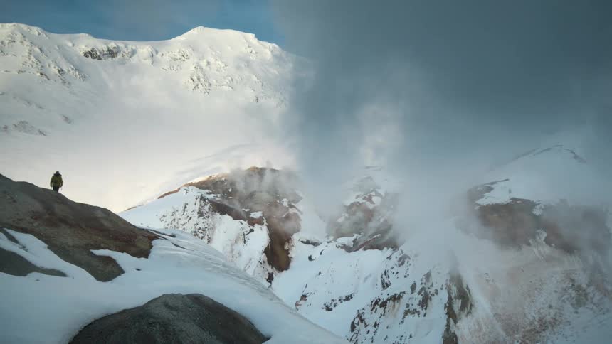 Person hiking up a snowy mountain during the day