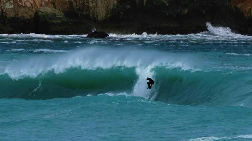 A man falls off his surfboard while surfing a wave