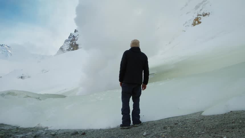 Man with his back turned in a natural space of glaciers and mountains