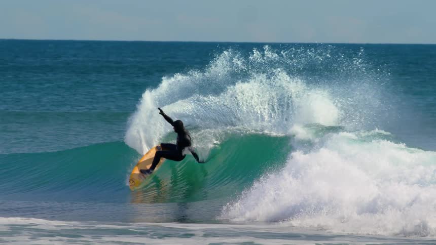 Person is surfing on large waves in the open sea