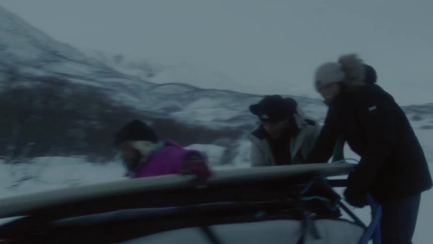 Person on a snowmobile carrying a rack with three other people and equipment on a foggy mountain