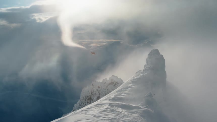 Helicopter flying over a snowy mountain with people in the background