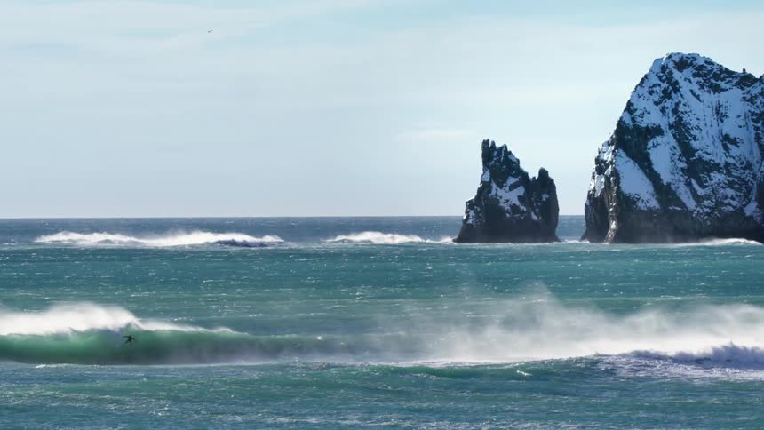 A person is surfing far out in the ocean
