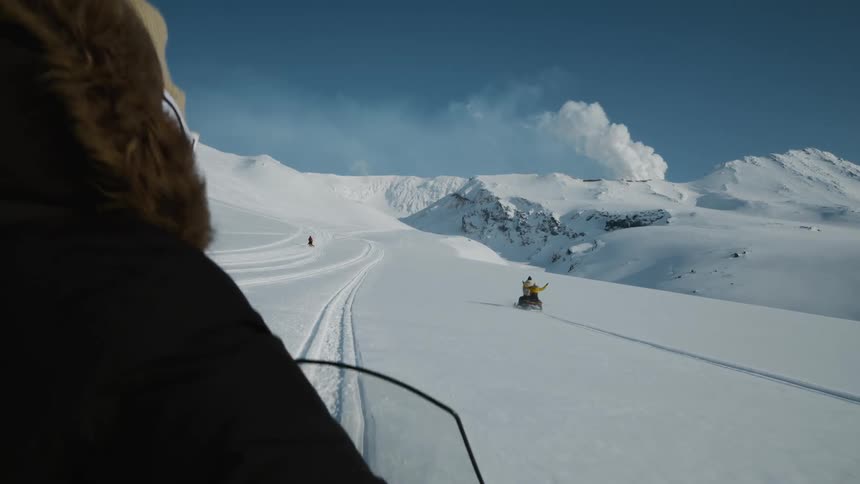 People riding snowmobiles on a snowy mountain during daytime
