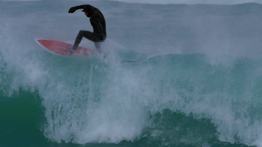 A man rides a large wide as he surfs