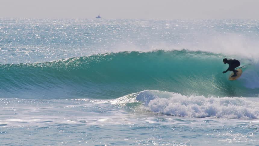 Slow motion of a man surfing on ocean waves during the daytime