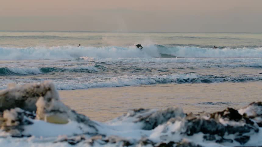 A person surfing a wave in the ocean and doing a maneuver in which he spins the board on the wave