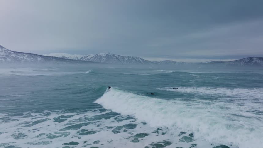 Three men are surfing in the arctic ocean